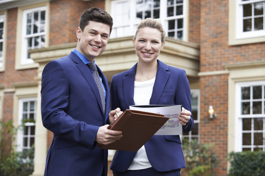 photo of Male And Female Realtor Standing Outside Residential Property